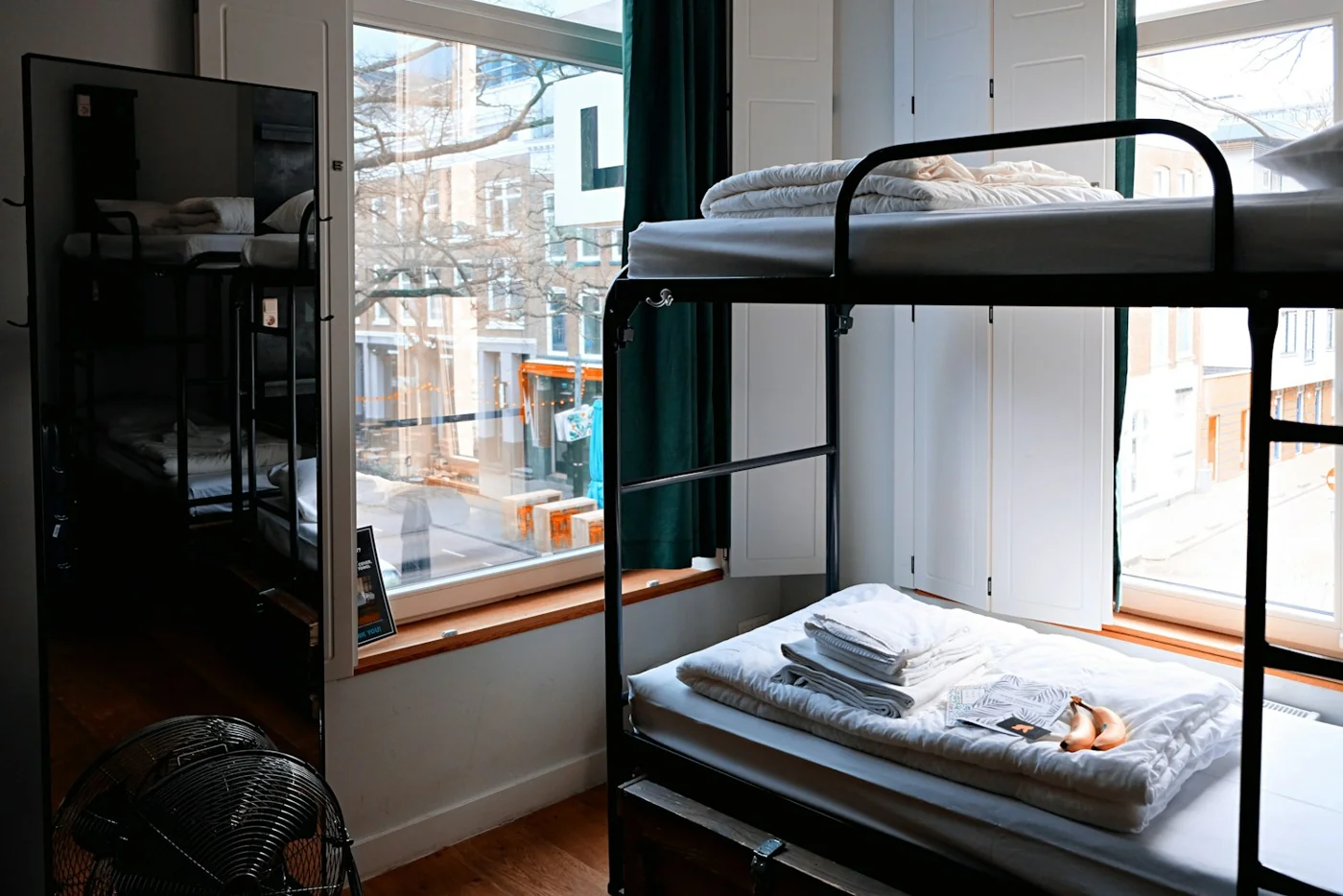 Un dortoir avec des lits superposés et une fenêtre sur la ville