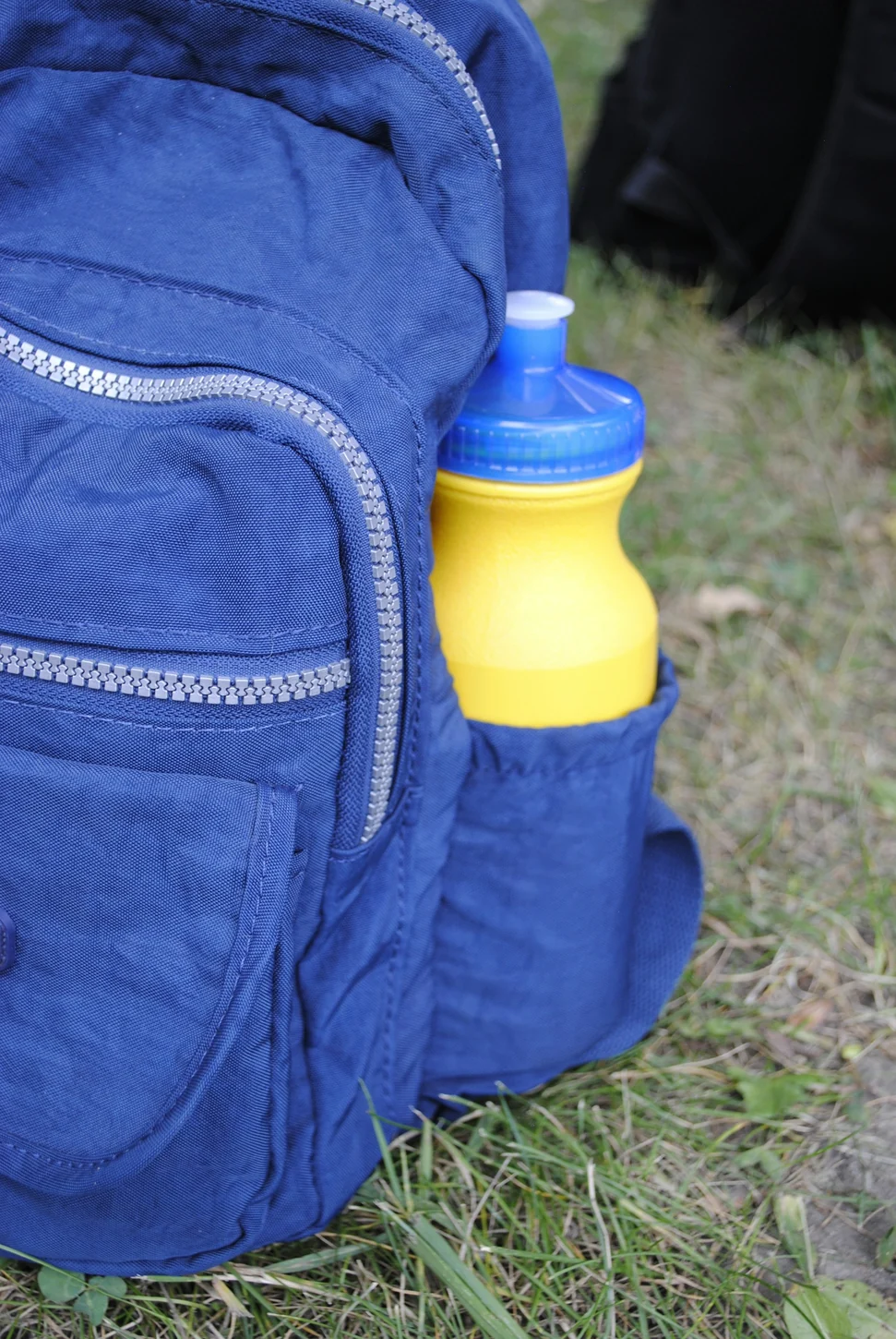 Gourde jaune dans la poche latérale d’un sac à dos bleu