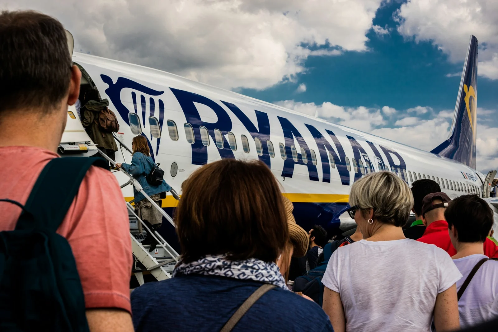 Voyageurs avec leurs sacs dans la file d’embarquement d’un avion Ryanair